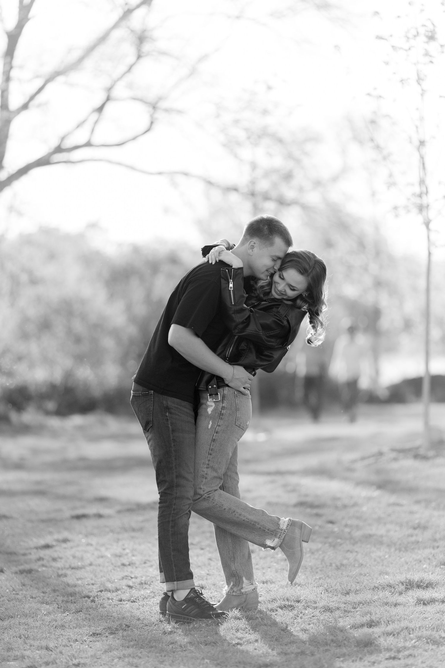 Playful black and white photo of couple laughing and embracing outdoors.