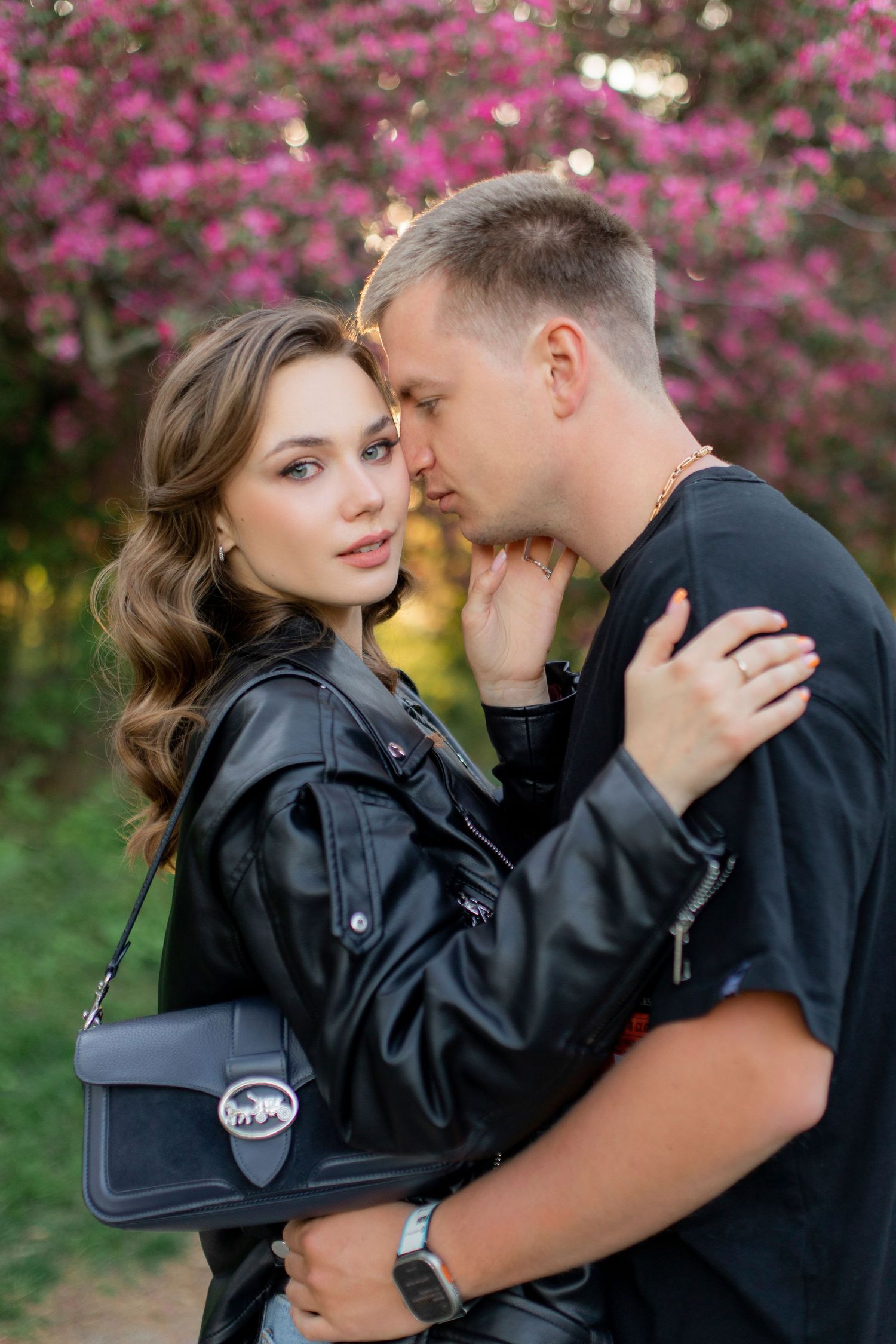 An intimate moment captured beneath blooming cherry blossoms in golden light.