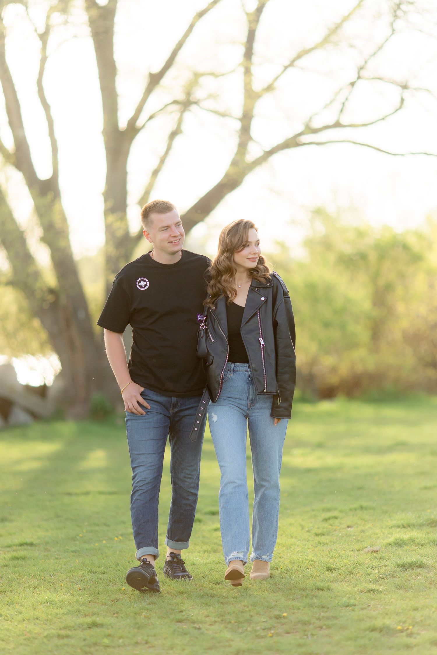 A couple takes a springtime walk together on grass during golden hour.