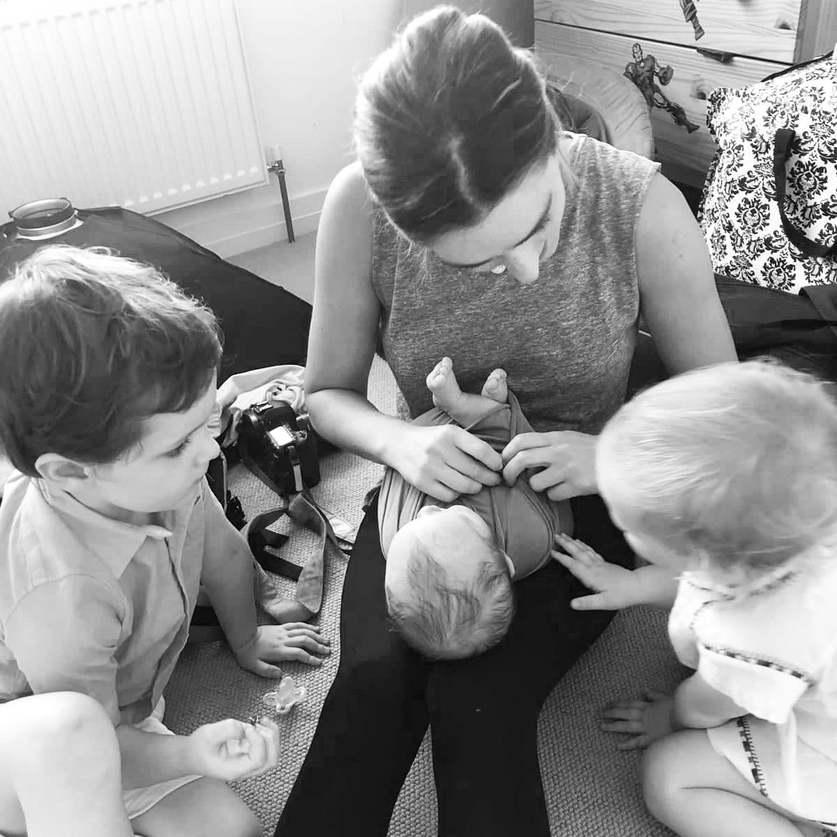 Black and white candid moment of young children gathered around looking at something.