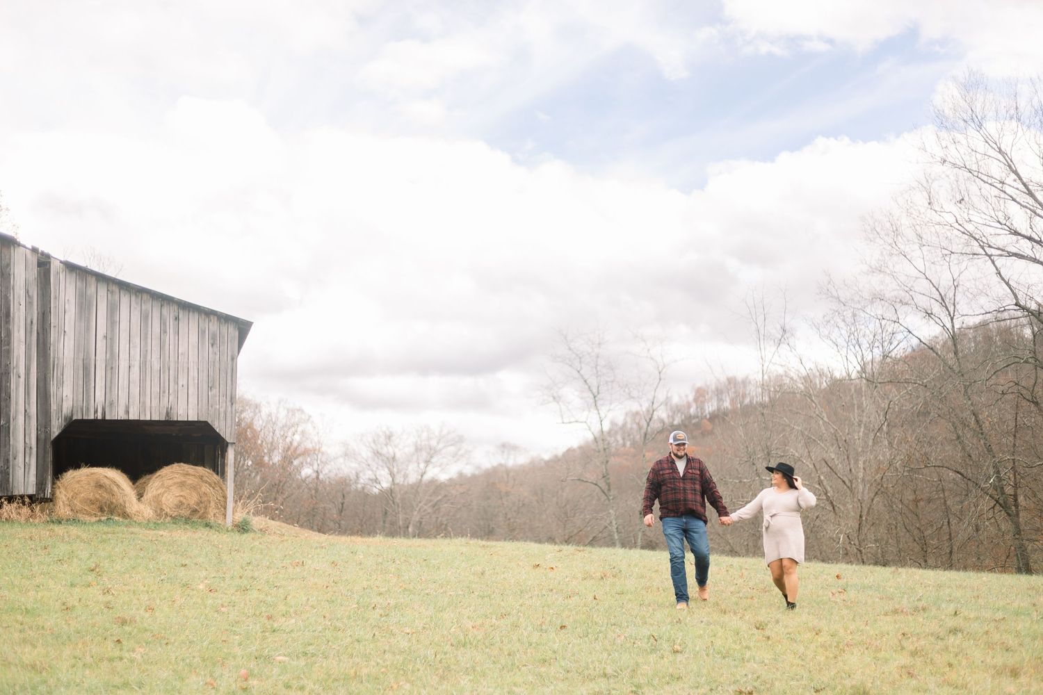 A romantic photoshoot in a scenic rural field with rolling hills in the background.
