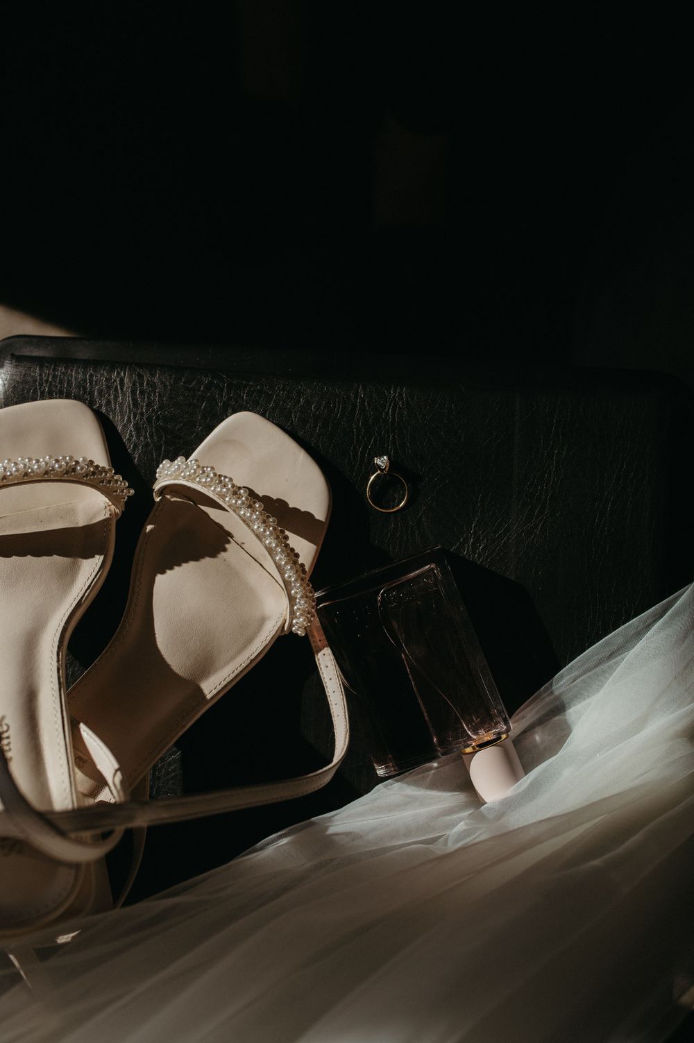 Elegant bridal heels and wedding accessories arranged artistically against a dark background.