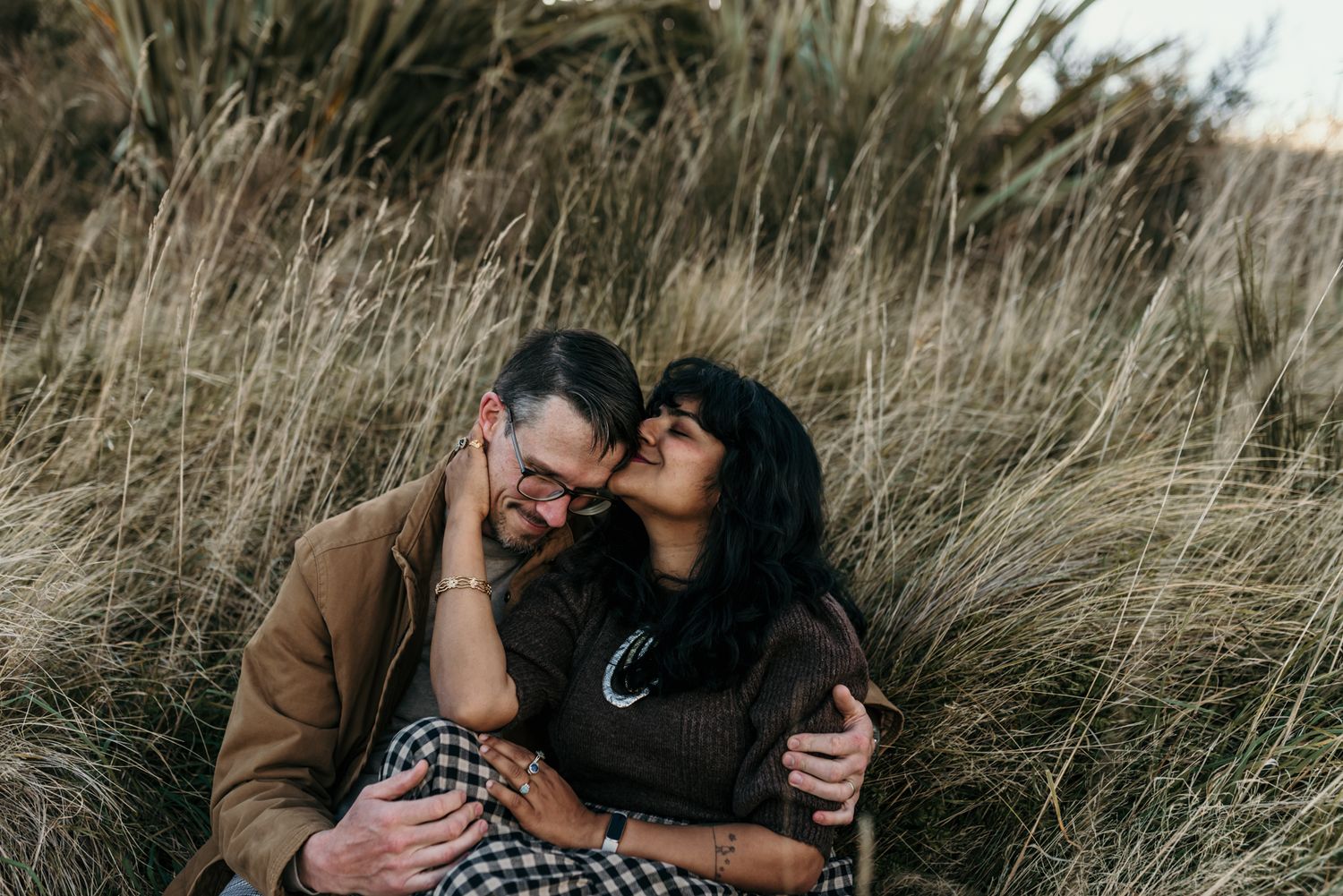 Couple sharing intimate moment while sitting in field of tall grass.