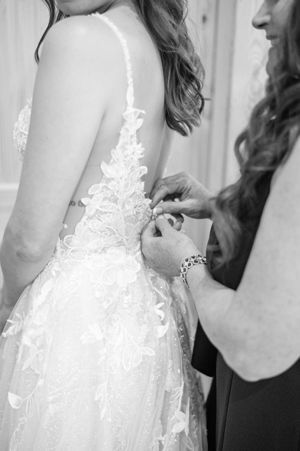 Black and white photo showing intricate lace detailing on back of wedding dress.