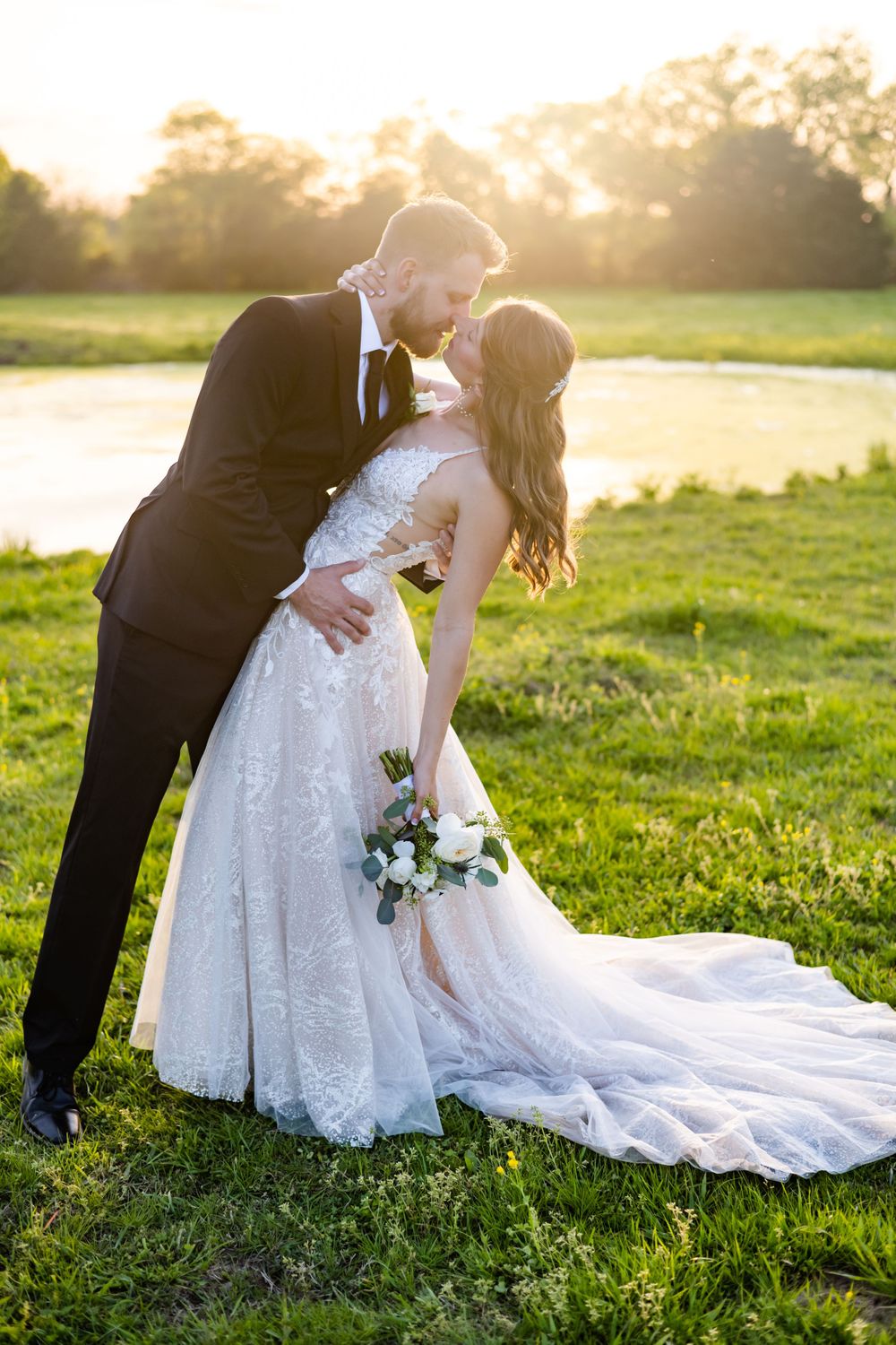 A romantic dip pose between newlyweds at sunset with flowing white dress.