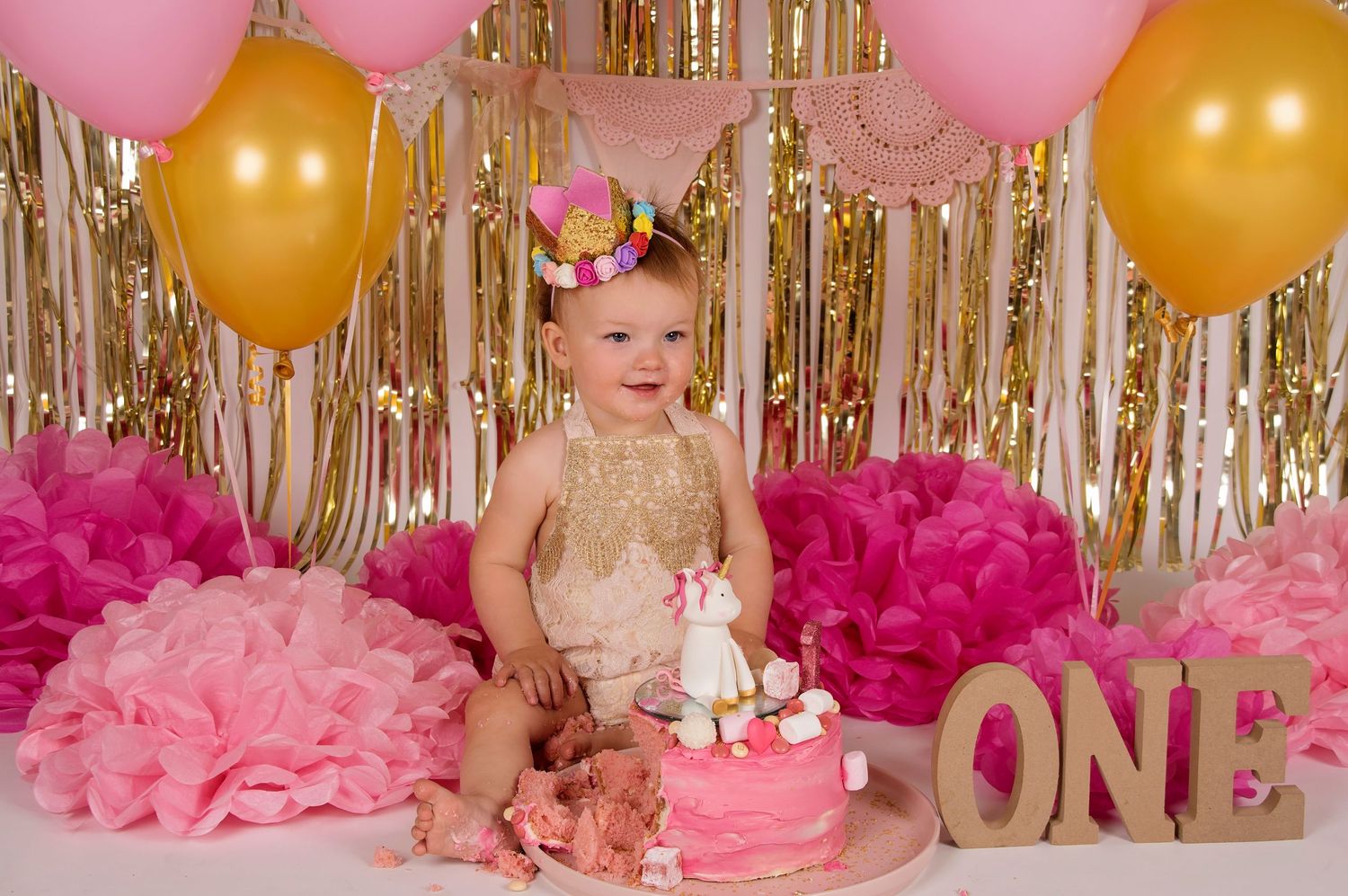 baby girl surrounded by pink decorations with pink cake