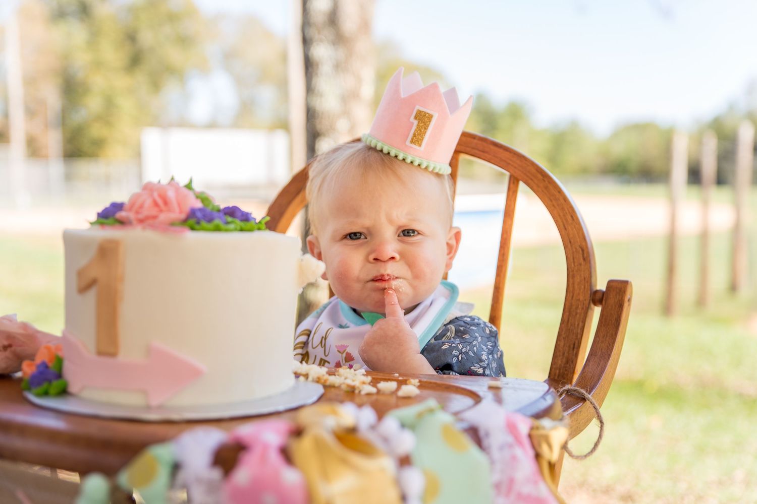 A One year old girl unsure about smashing a cake