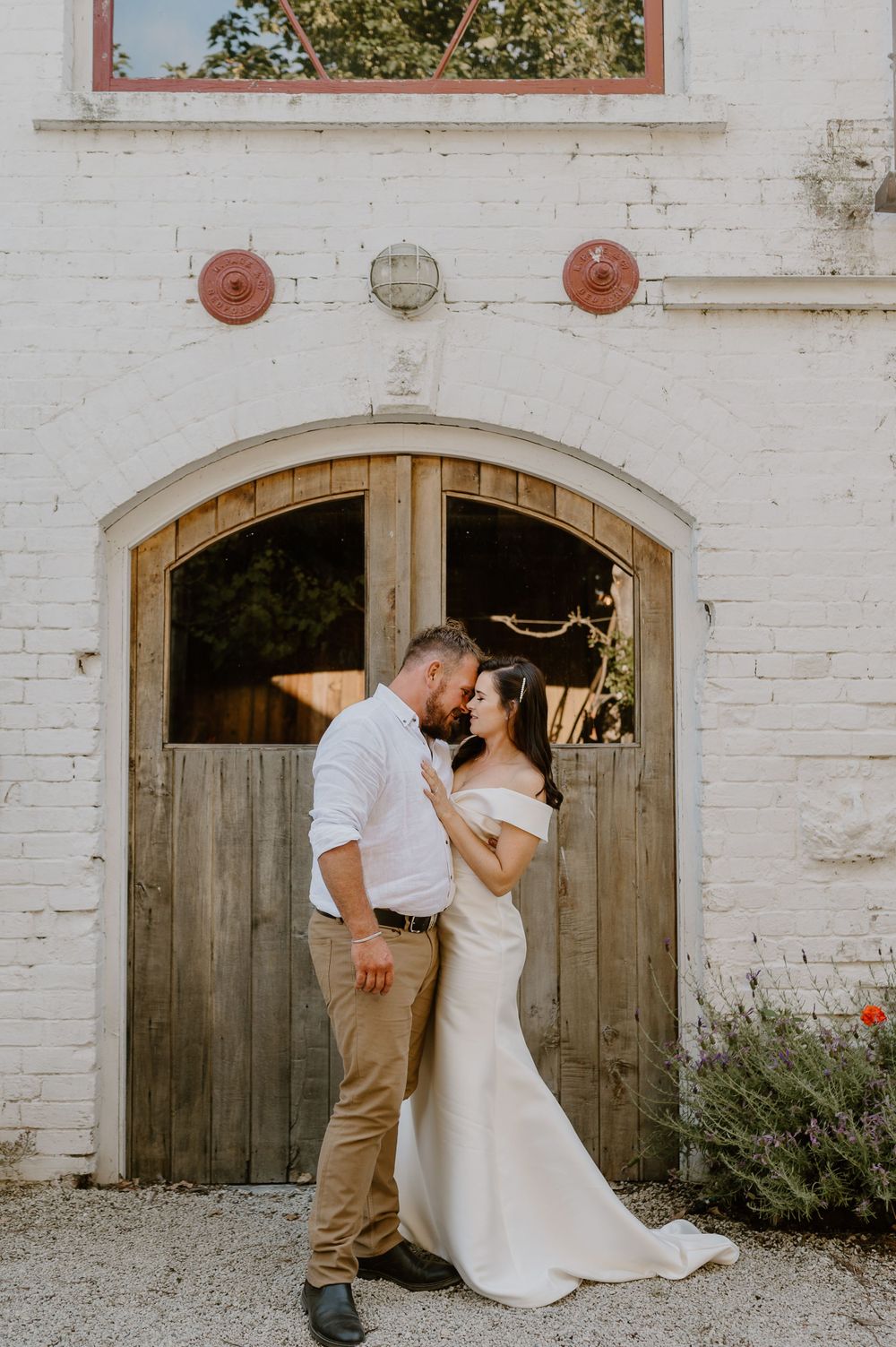 A romantic wedding photo at a rustic white barn door with vintage architectural details.