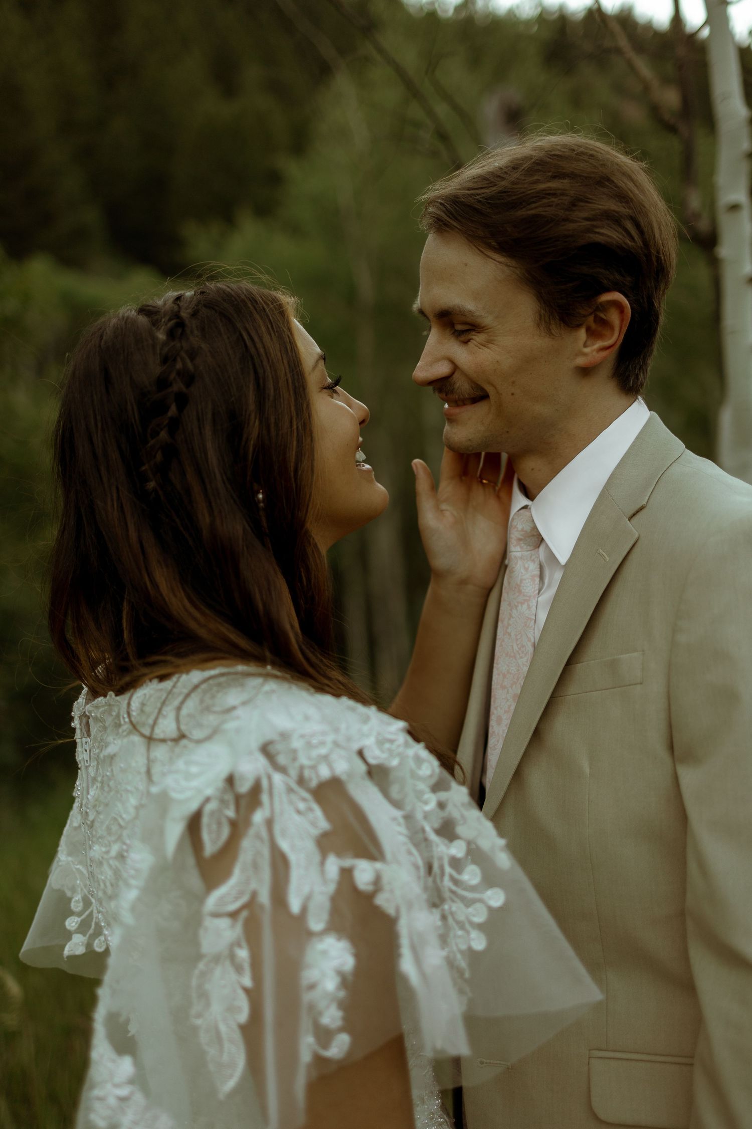 Close-up of bride and groom touching faces and smiling big at each other