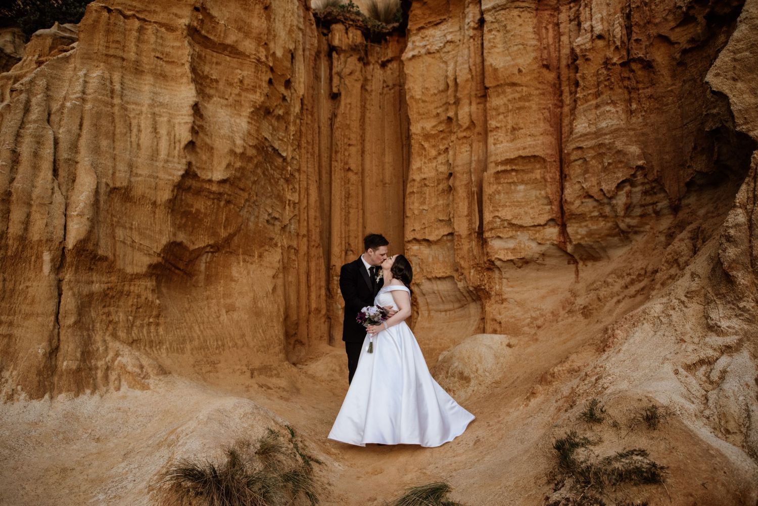A dramatic wedding portrait against towering orange sandstone cliffs.