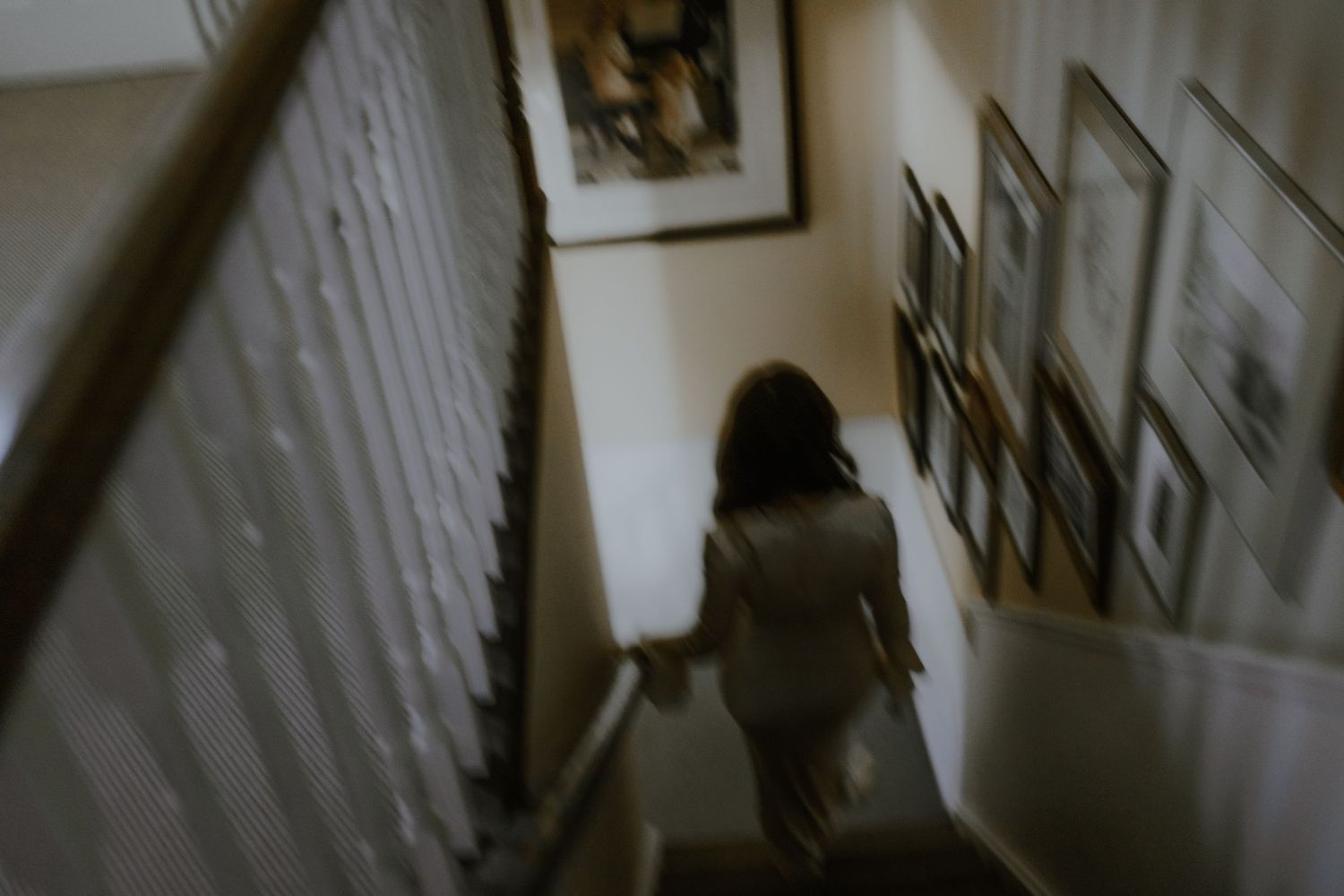 a motion blurred image of a bride descending a staircase for her family to see