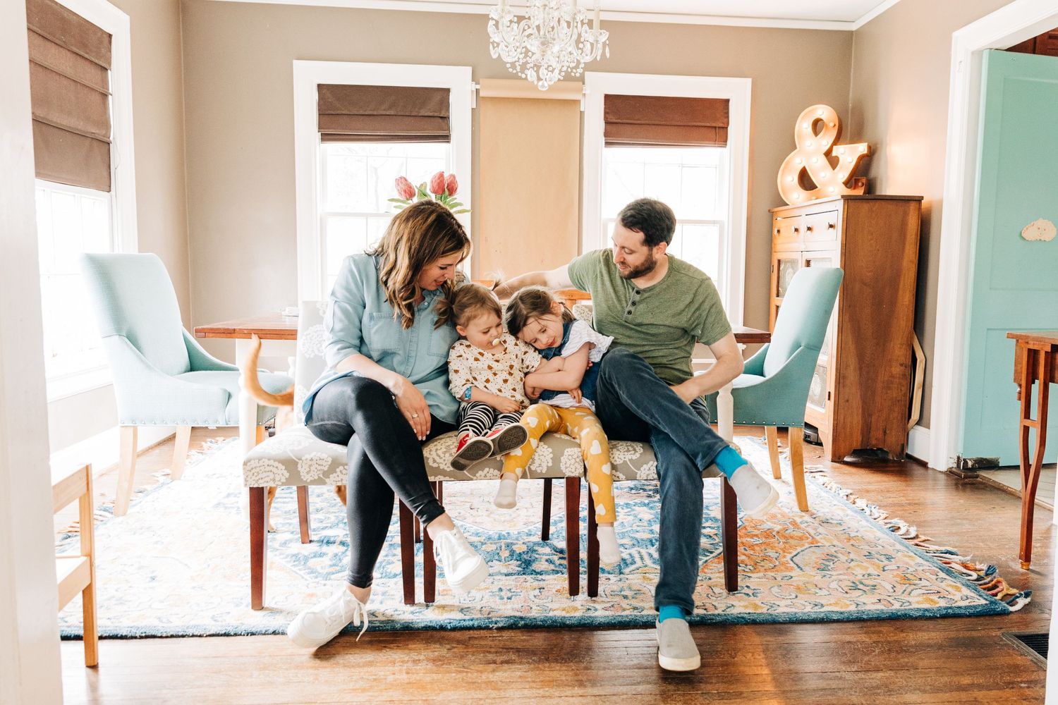 Charlotte family cuddles on a bench in their dining room for photos
