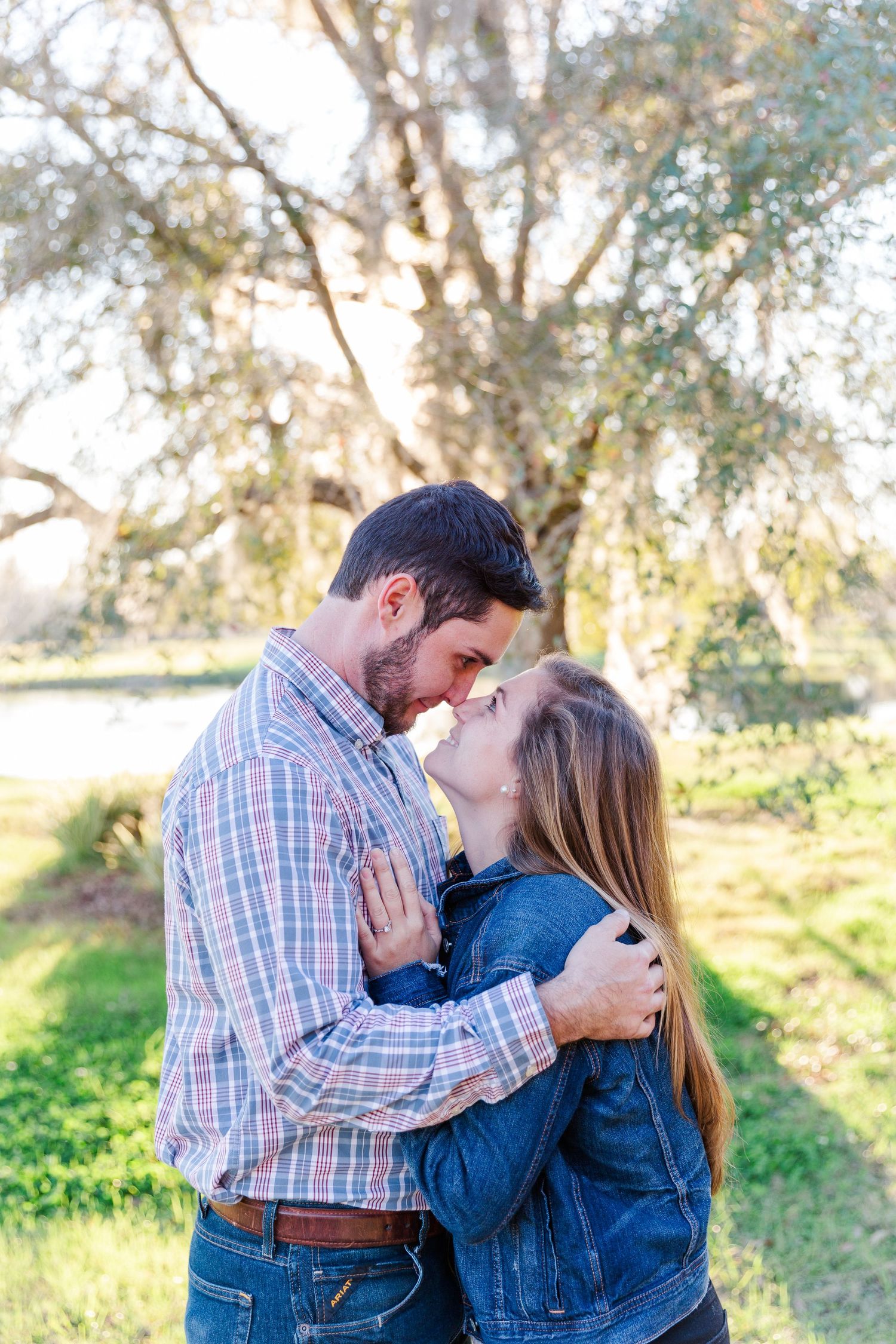 Romantic outdoor photoshoot in casual attire against natural sunlit backdrop.