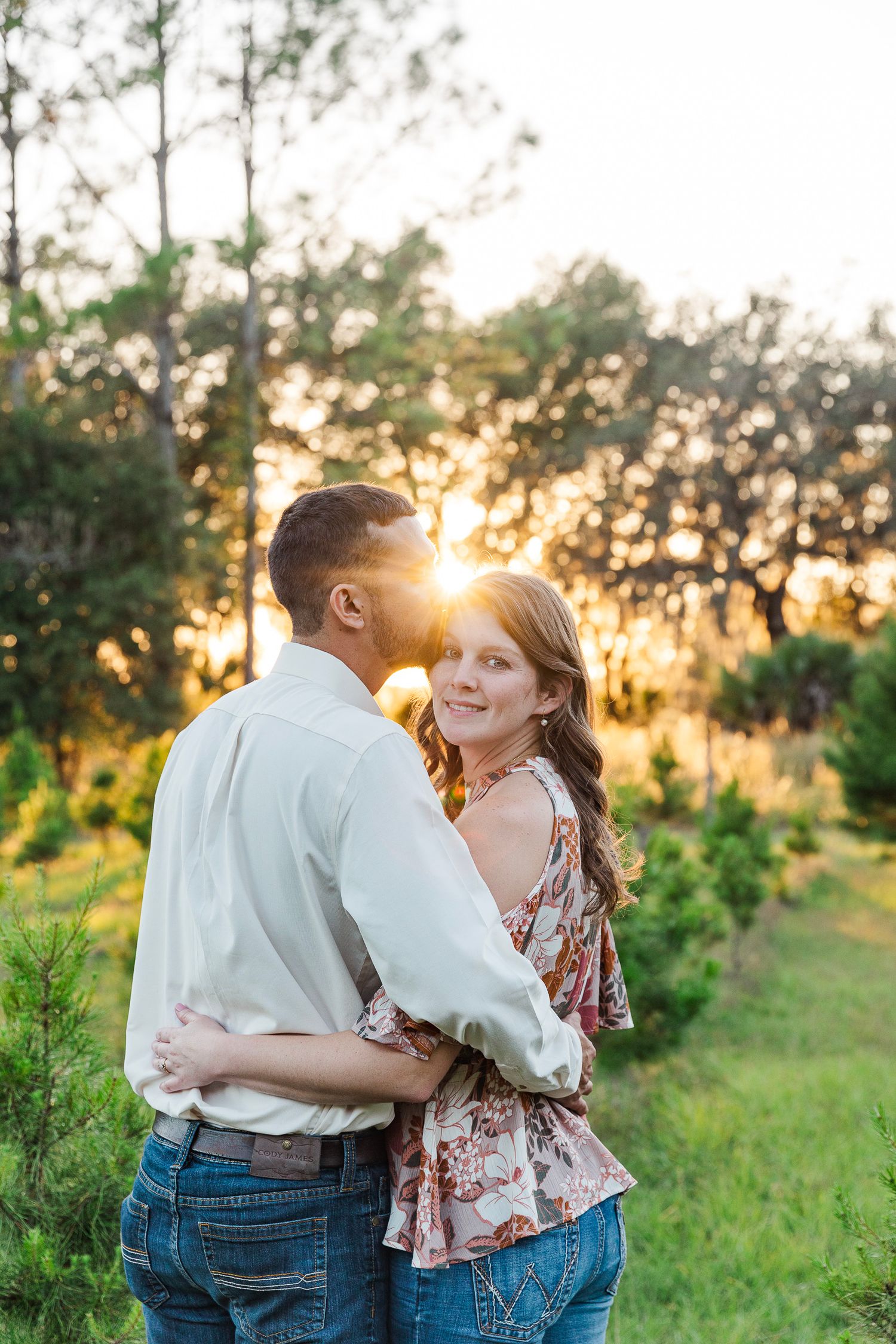Sunset engagement photos in a grassy field with golden backlight.