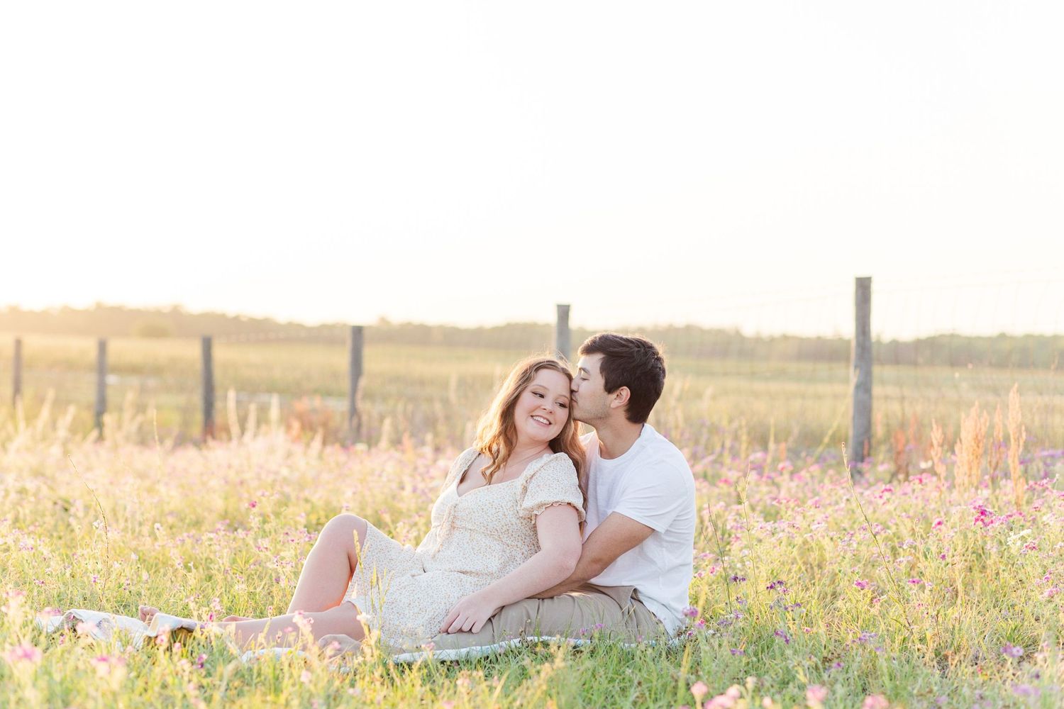 Couple relaxing in golden field during sunset photoshoot.