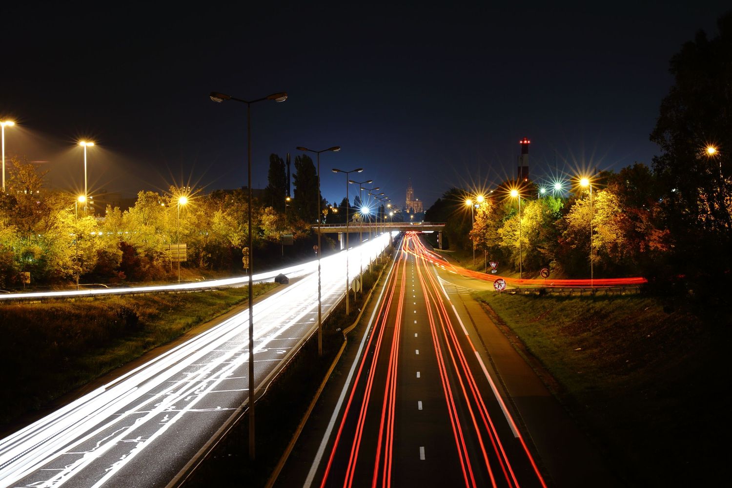 Long exposure of highway traffic creating light trails through a city at night.