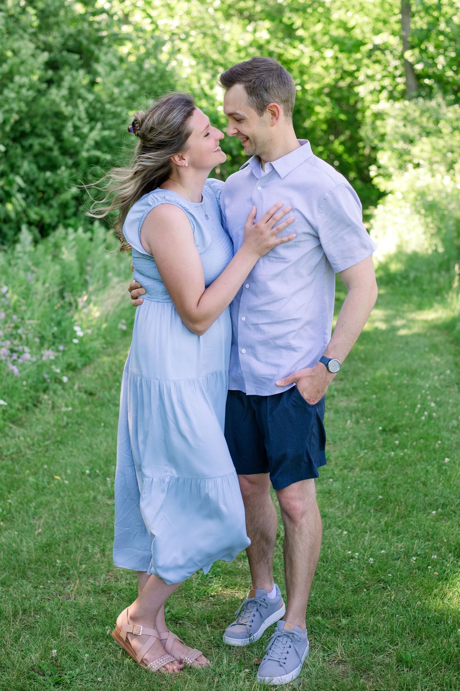 A couple in coordinating blue and white outfits share an intimate moment outdoors.