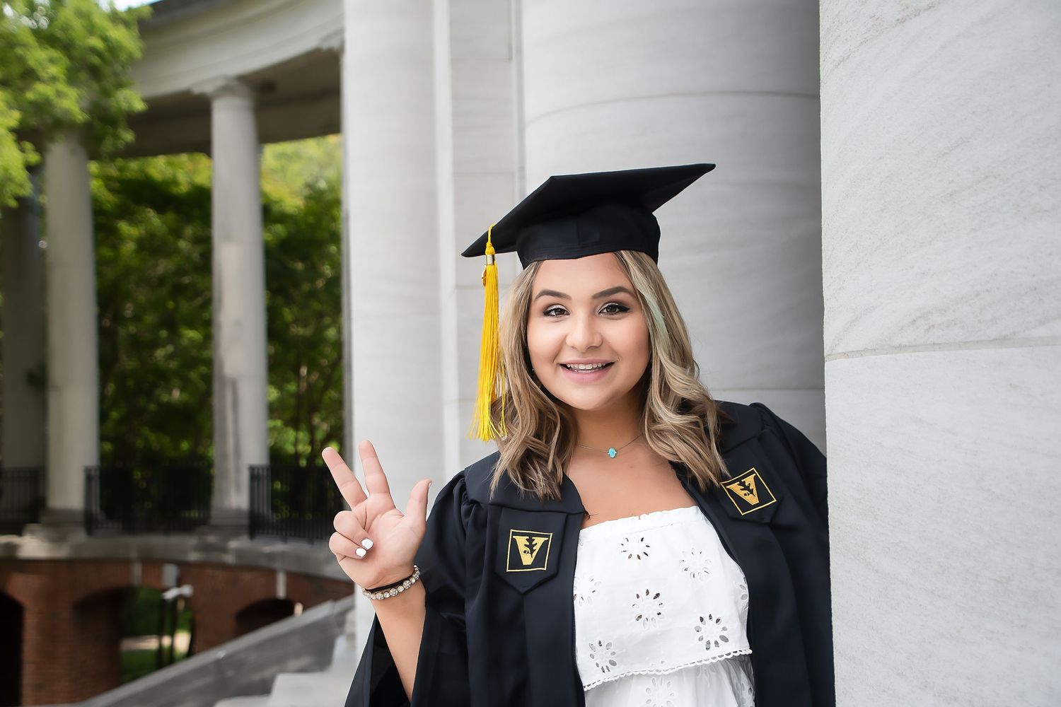 Graduation photos with cap and gown in front of white columned building.