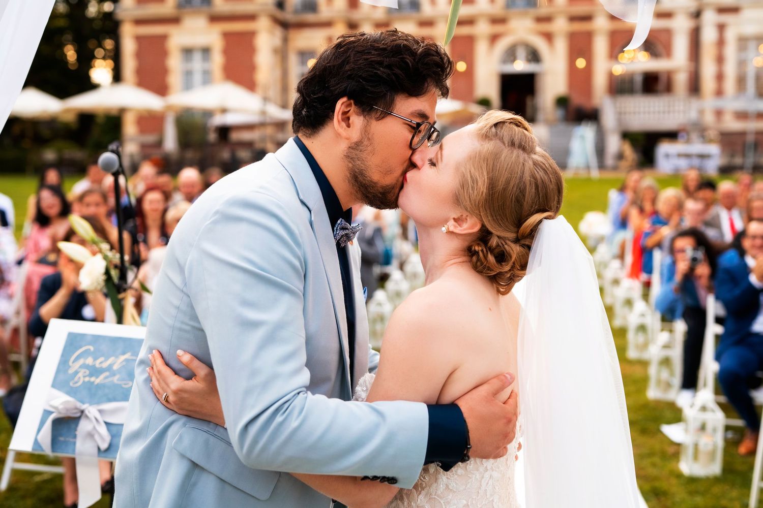 Newlyweds share romantic kiss during outdoor garden ceremony.