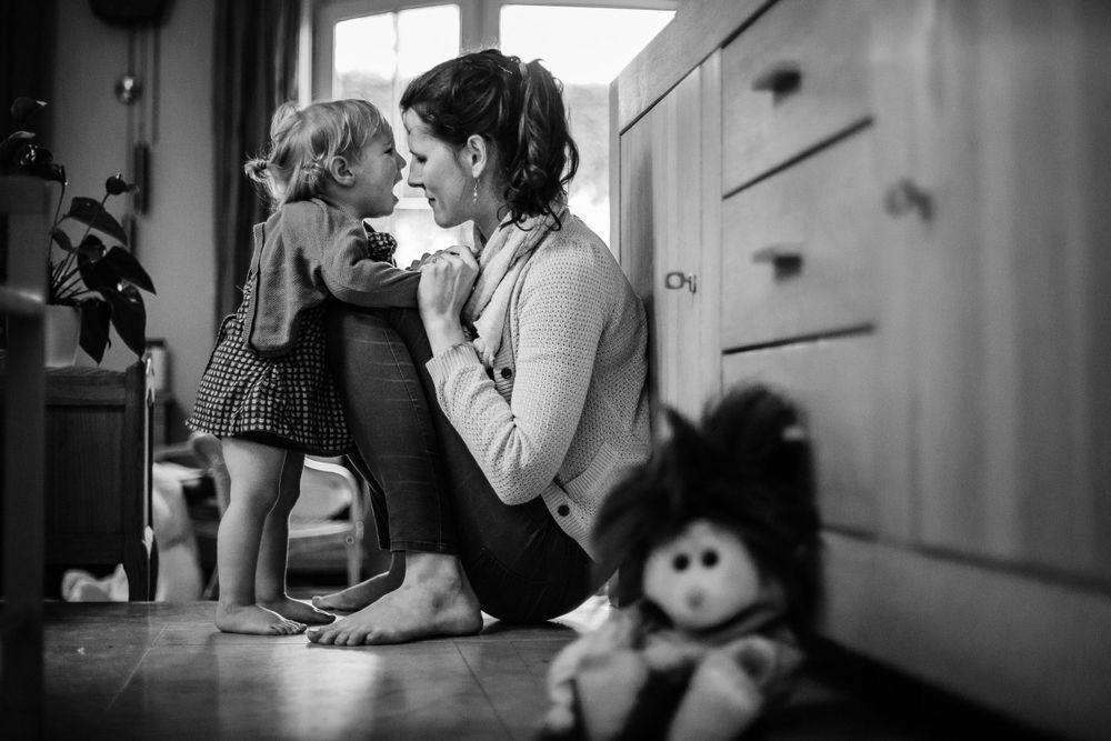 Black and white interior photograph showing everyday moments near kitchen cabinets.