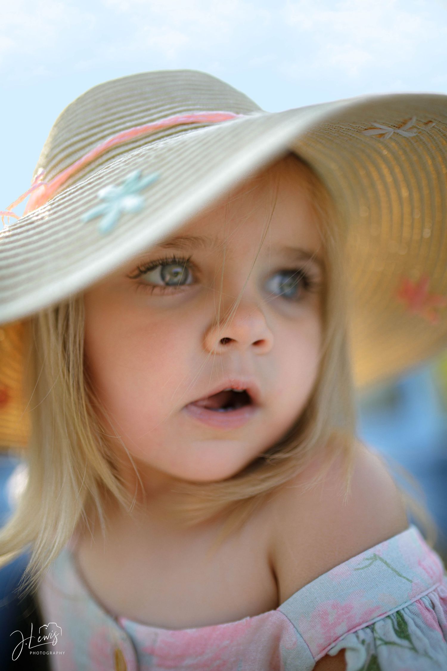 A close-up portrait of a child wearing a decorative sun hat with delicate features.