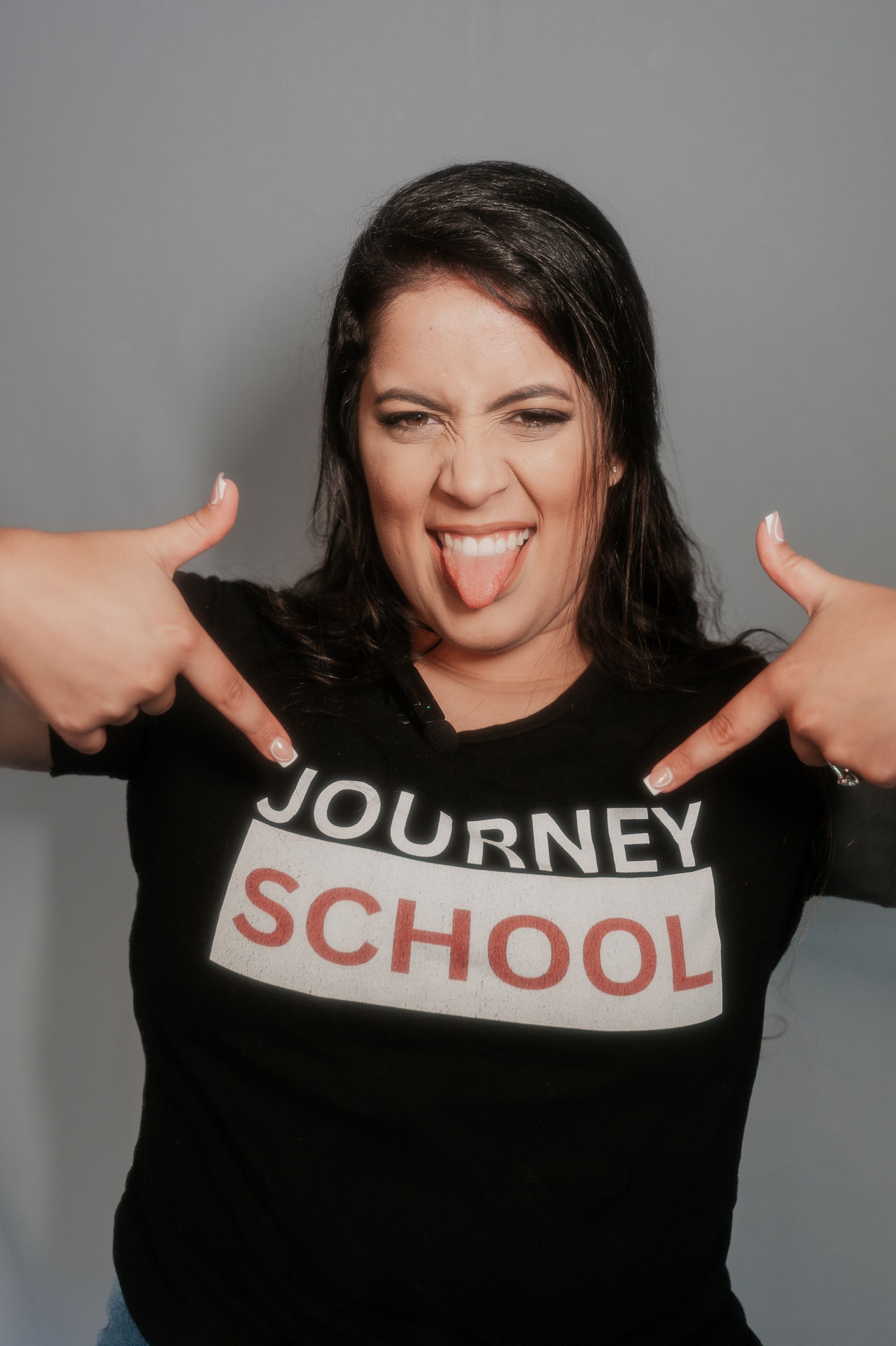 Energetic portrait of person wearing Journey School t-shirt making playful gesture.