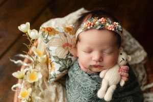 Newborn girl on a floral pillow holding a tiny bear. - Greenville SC newborn photographer - Easley SC newborn photographer