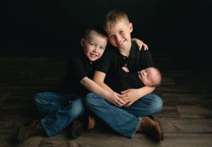 2 older brothers holding their newborn brother. - Greenville SC newborn photographer - Easley SC newborn photographer