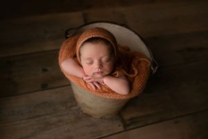Newborn girl in a bucket with hands resting on edge. - Greenville SC newborn photographer - Easley SC newborn photographer