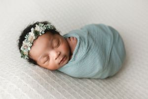 A black newborn girl wrapped in a beautiful blue color with a flower headband. - Greenville SC newborn photographer - Easley SC newborn phot