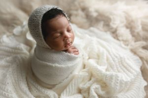 An African American newborn wrapped in a cream wrap and on cream blankets. - Greenville SC newborn photographer - Easley SC newborn photogra