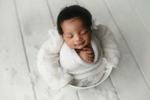 A Black newborn girl with a head full of hair in white.