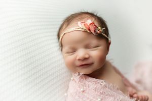 a smiling newborn girl in pink wrap with a pink headband. - Greenville SC newborn photographer - Easley SC newborn photographer