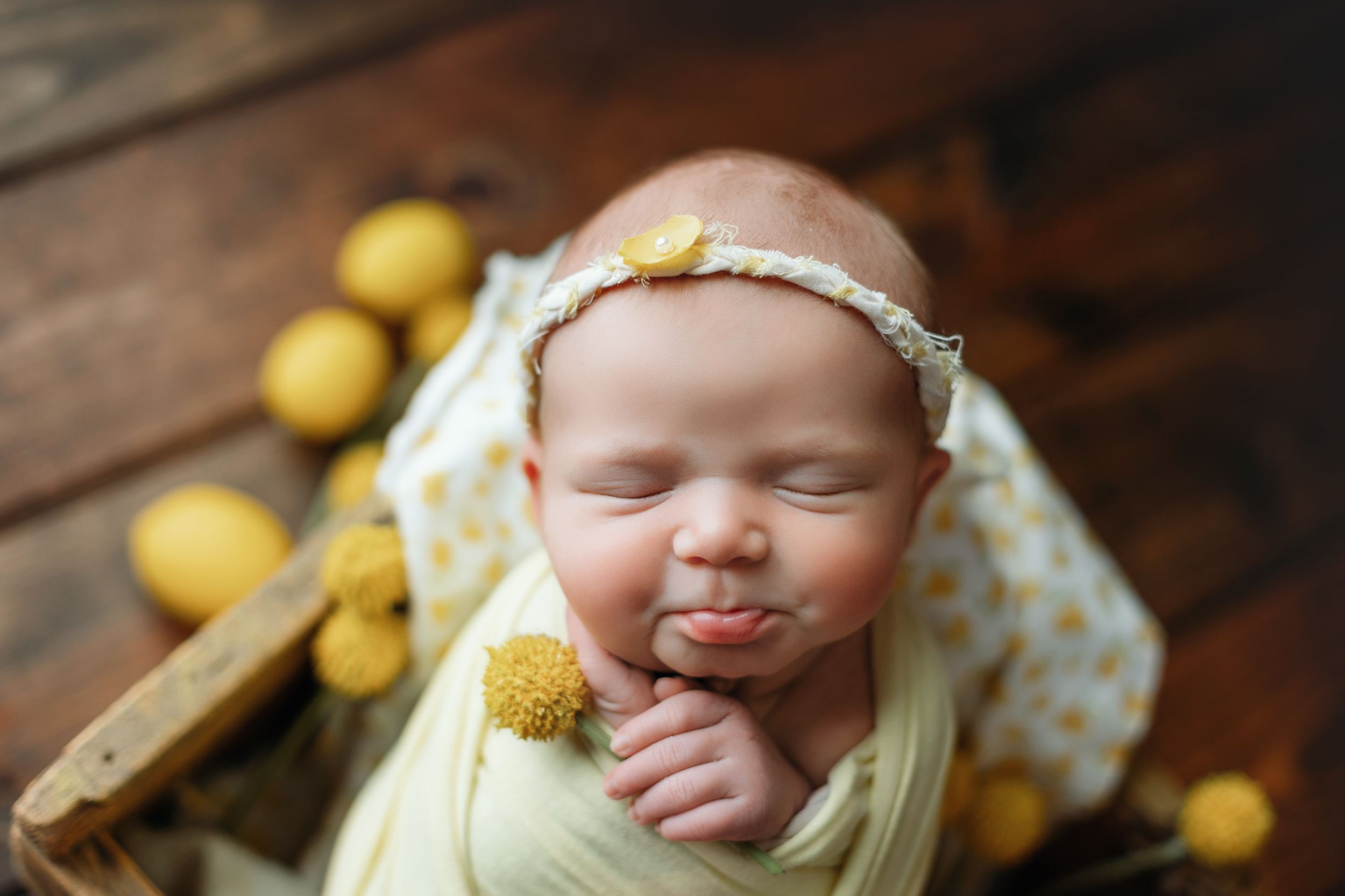 Newborn girl wearing light yellow and holding a yellow poppy ball. - Greenville SC newborn photographer - Easley SC newborn photographer