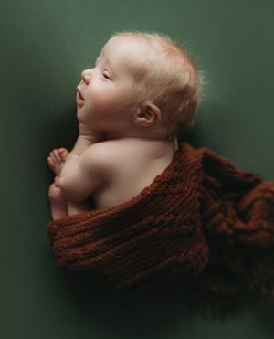 Newborn boy on a green backdrop with a brown wrap doing the taco pose. - Greenville SC newborn photographer - Easley SC newborn photographer