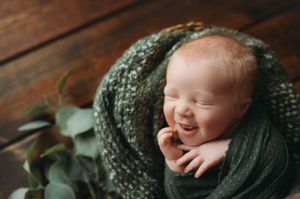 Newborn boy smiling in hunter green wrap. - Greenville SC newborn photographer - Easley SC newborn photographer