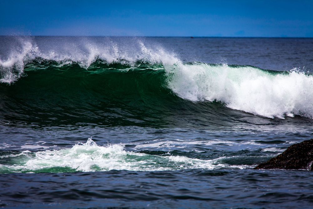 Powerful ocean wave crests with white foam against deep blue waters.