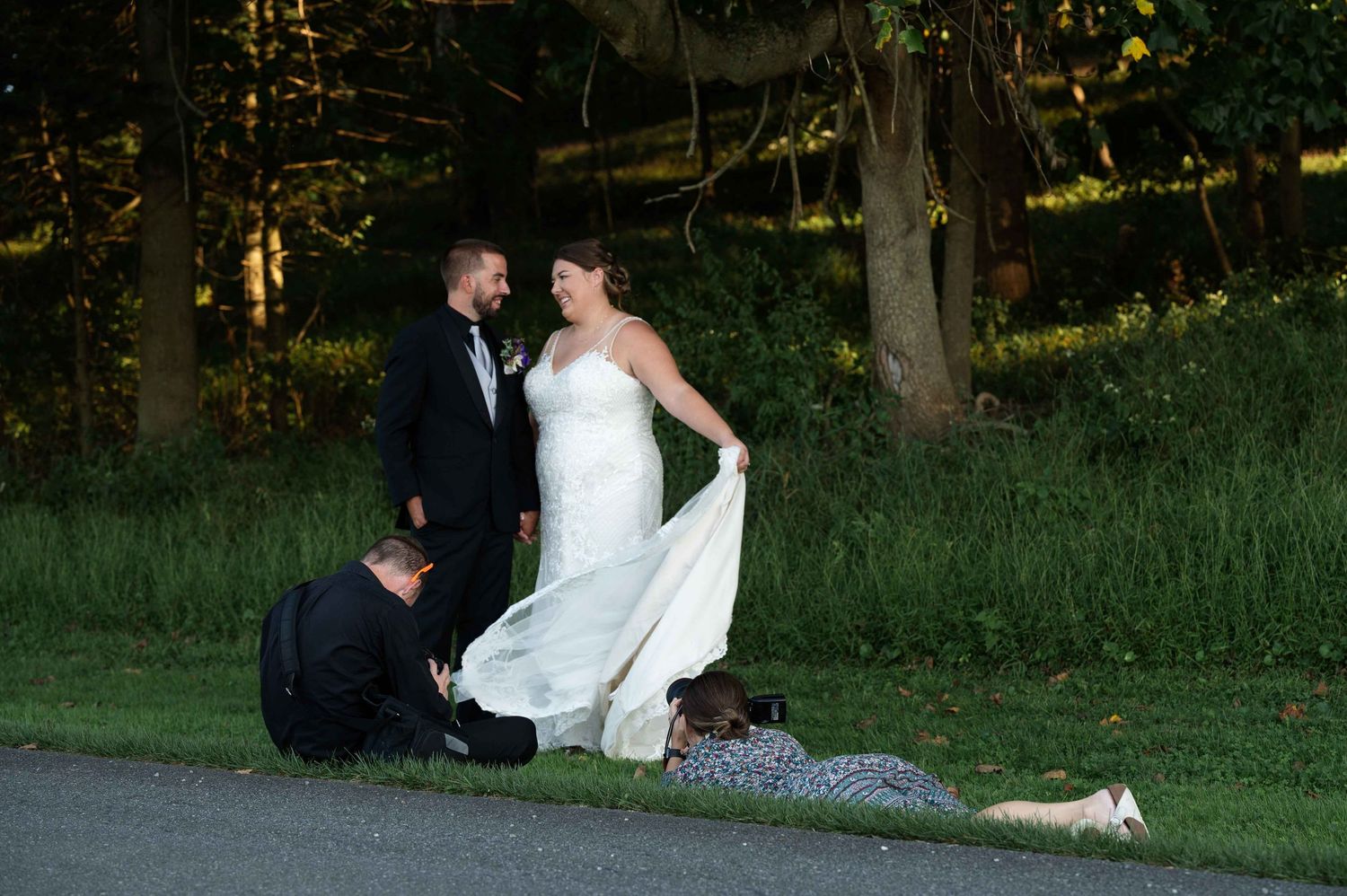 Wedding photo session on a path at dusk with dress adjustments being made.