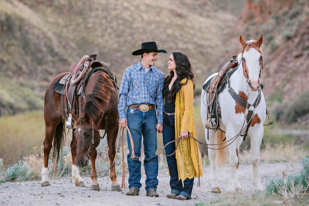 Engaged couple poses in the Owyhee Desert with horses