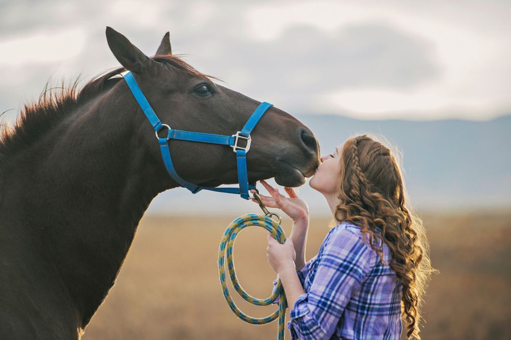 Senior girl kissing her horse at her family ranch in Vale, Oregon