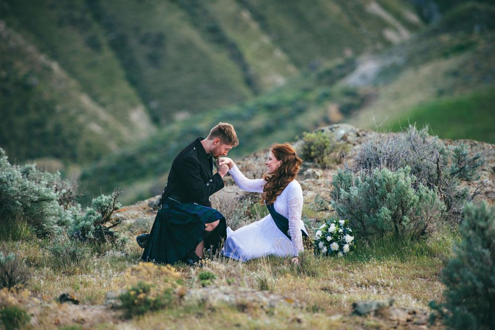 A groom wearing a kilt kisses his bride's hand in the Owyhee desert in Eastern Oregon