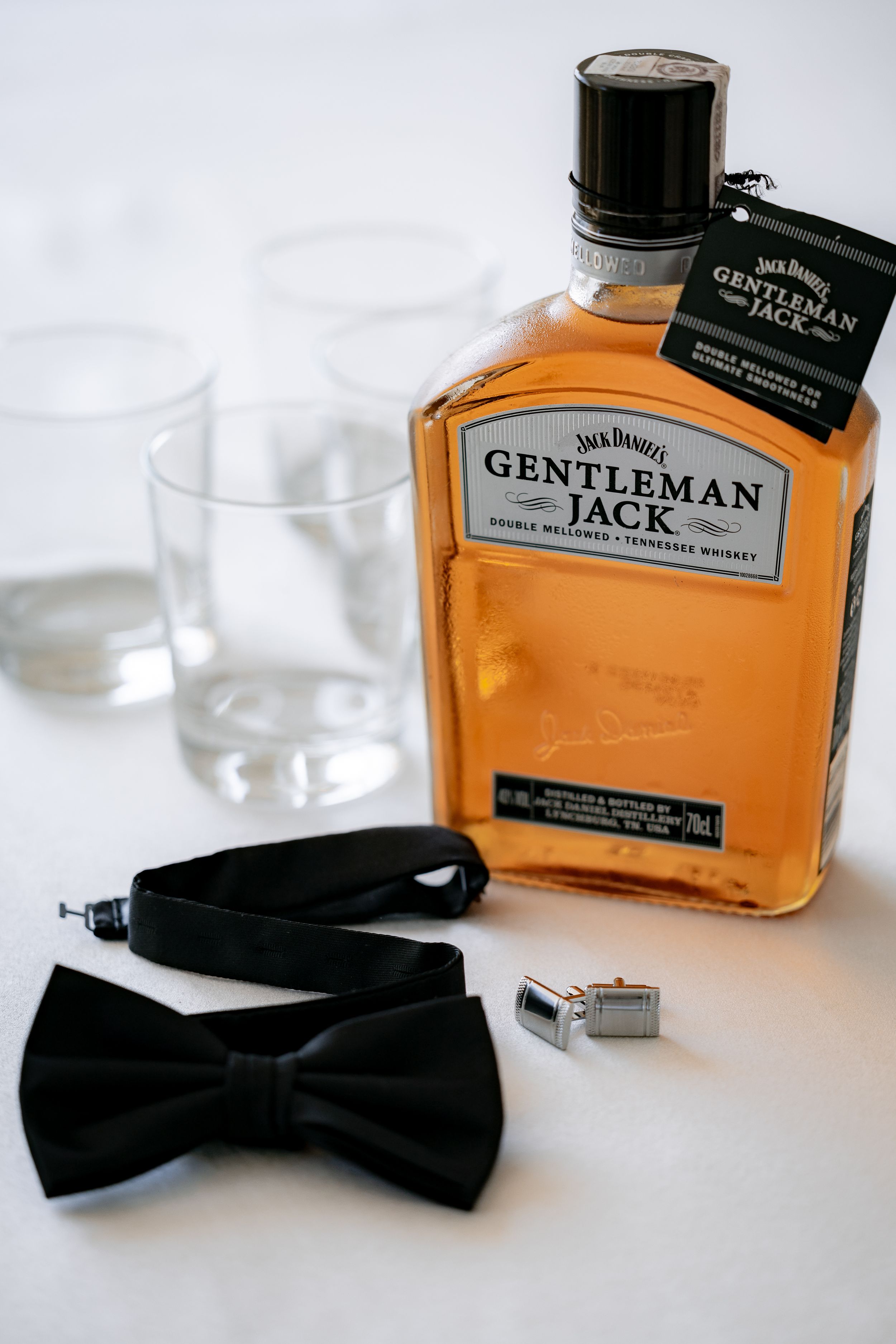 Gentleman Jack whiskey bottle with bow tie and cufflinks for wedding preparation.