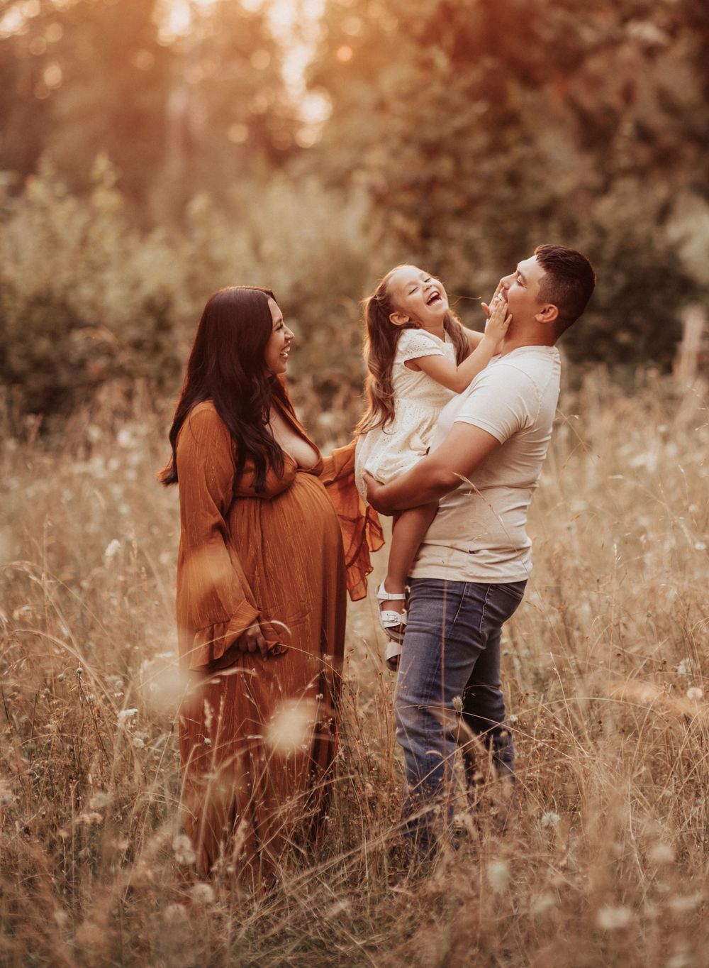 Casual outdoor family portraits captured in warm evening light among tall golden grass.