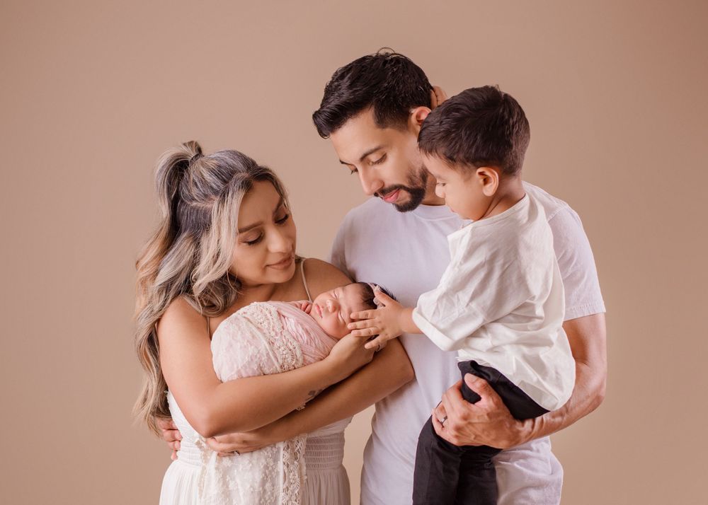 Family of three sharing intimate moment while admiring their newborn baby.