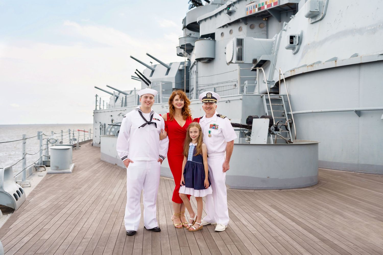 Family pose on the deck of a naval ship in formal attire.