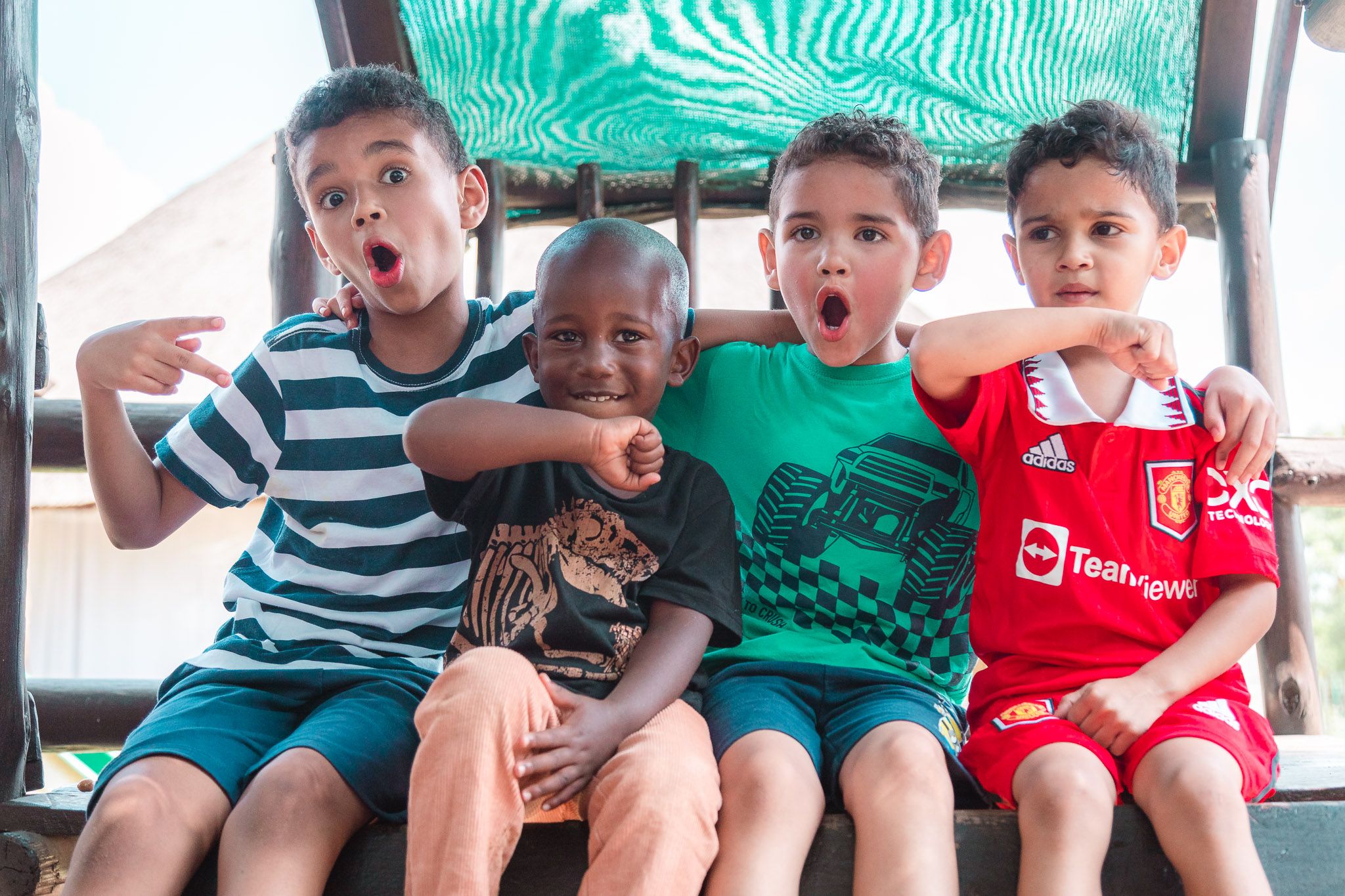 Four young boys sitting on a wooden climbing frame demonstrating their personal superhero style