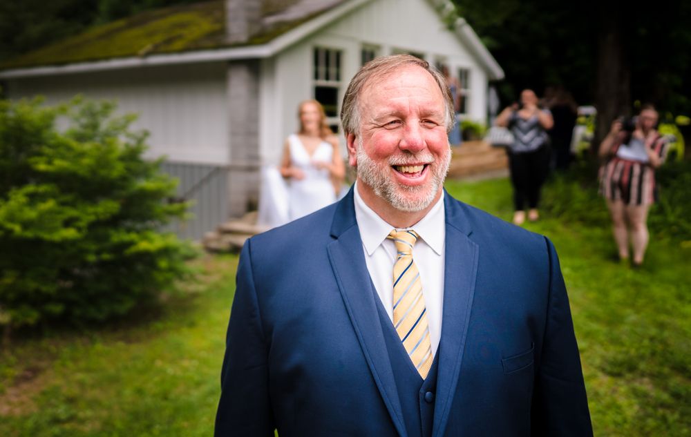 Wedding party members in navy suits and yellow ties standing outdoors on a sunny day.