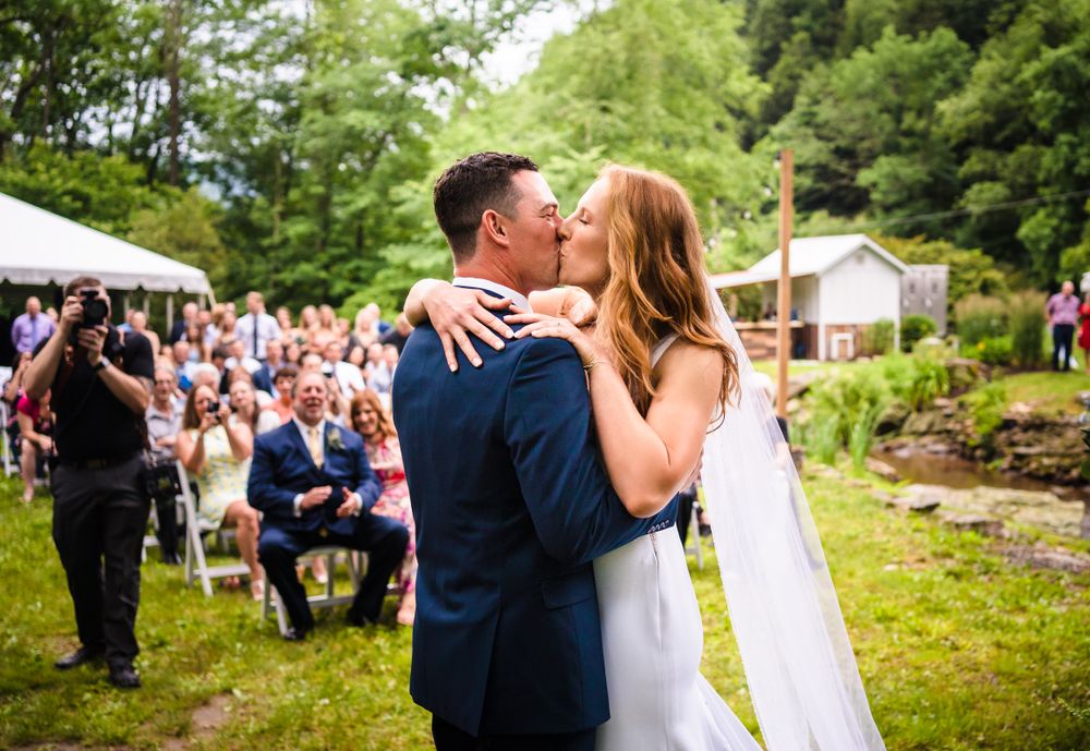 Couple shares an intimate moment during outdoor wedding photoshoot surrounded by lush greenery.