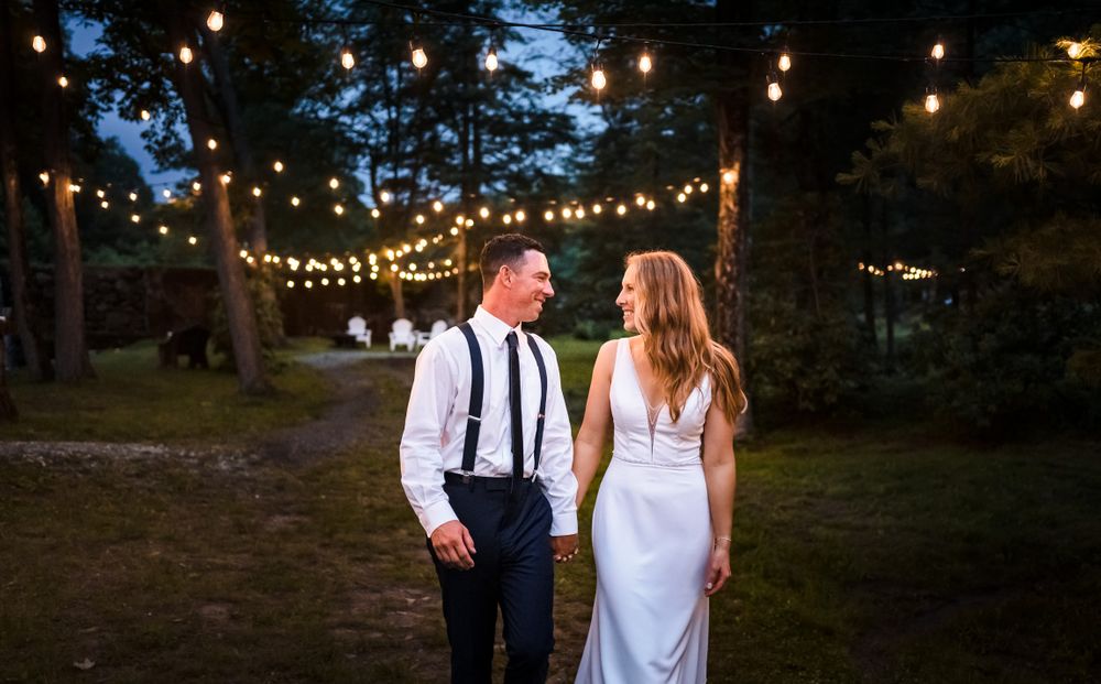 String lights illuminate outdoor wedding reception as evening falls.