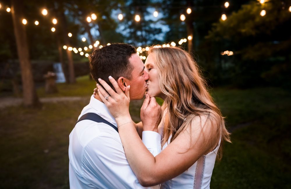 Romantic couple shares an intimate moment under twinkling lights at dusk.